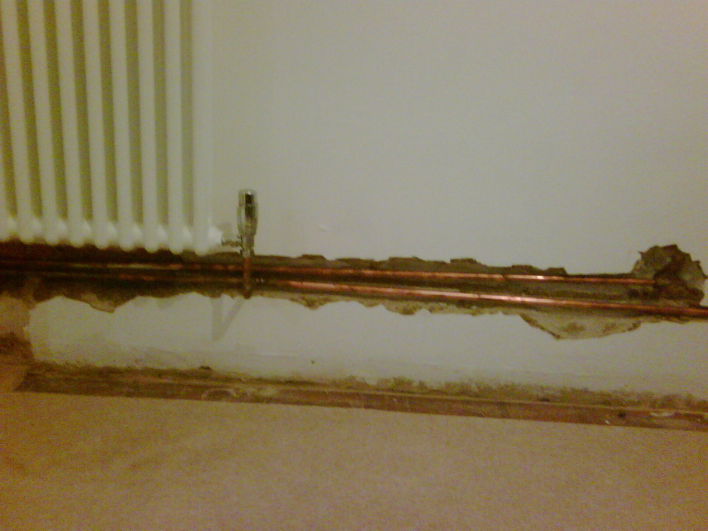 Make good wall around radiator where pipes chased in Plastering job